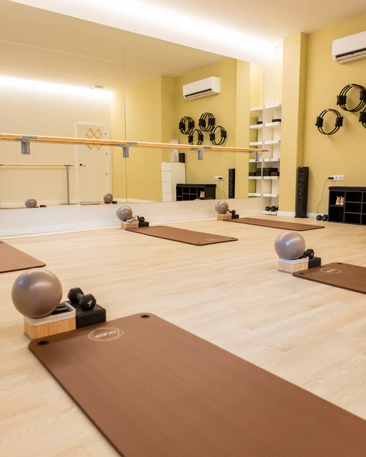 Sala de Pilates preparada para una clase, con esterilla, pelota y lastres en cada puesto